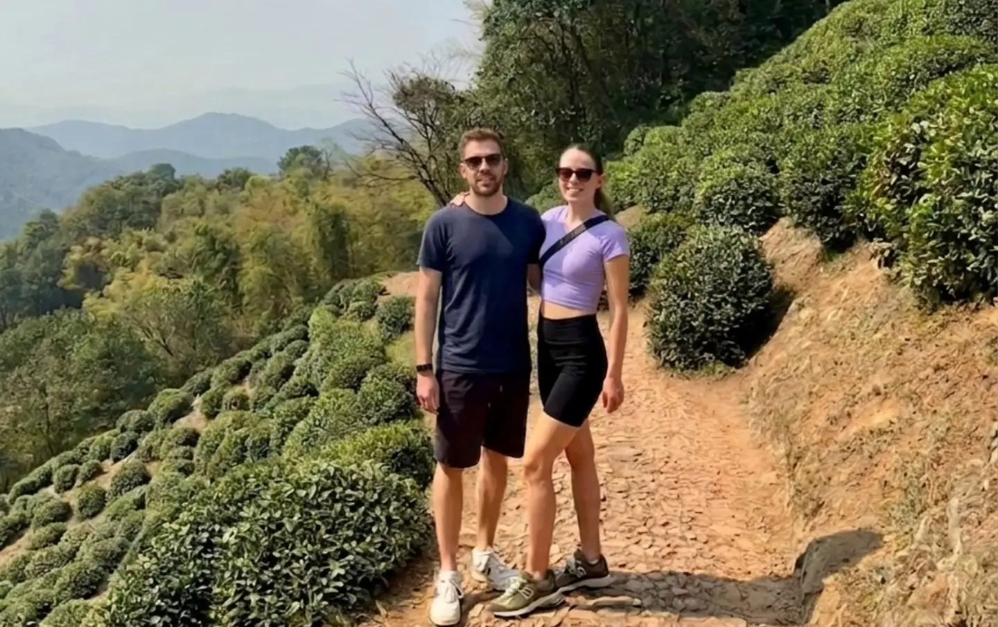 Western couple exploring Longjing tea plantation hills in Hangzhou scenic countryside