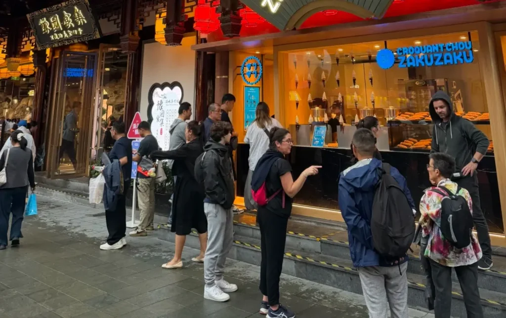 Tourists queuing for street food in a busy Shanghai market street