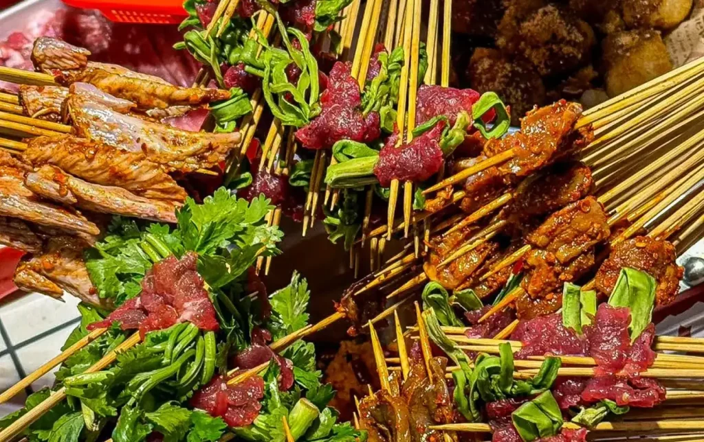 Assorted Chengdu chuanchuanxiang skewers with meat and herbs served in spicy Sichuan sauce
