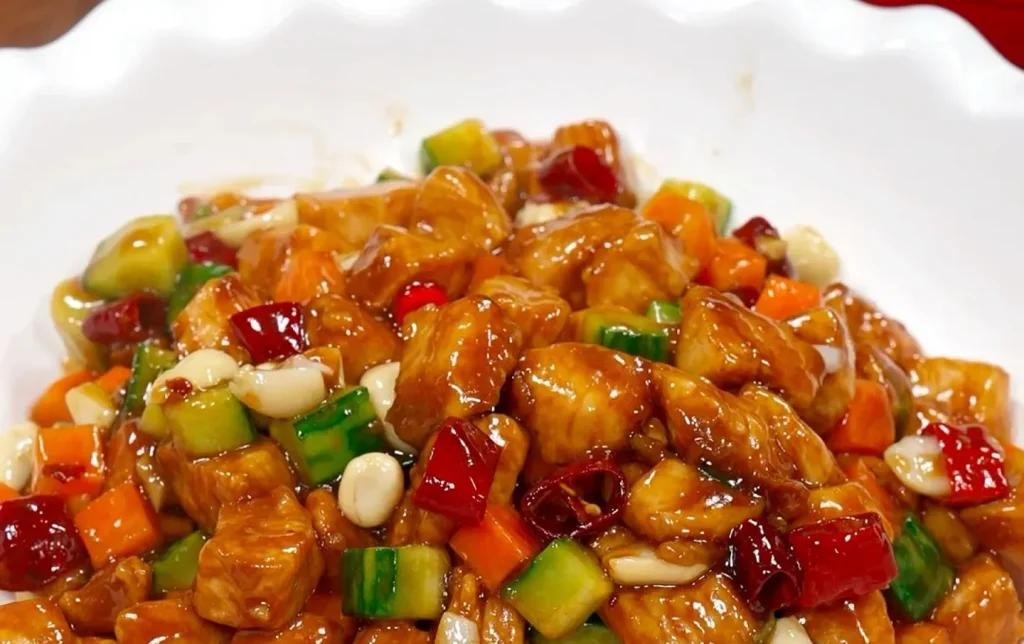 Classic Sichuan kung pao chicken with peanuts dried chili peppers and vegetables in white bowl