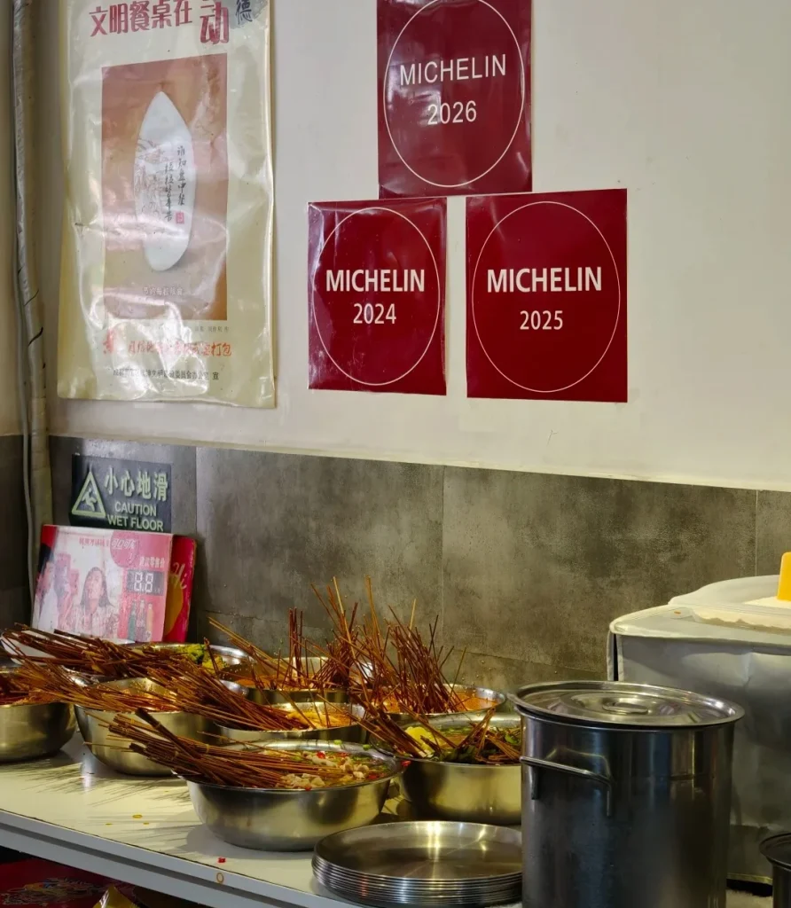 Michelin-awarded bobo chicken restaurant in Yulin, Chengdu, showing 2024 2025 2026 Michelin plaques above spicy skewer bowls