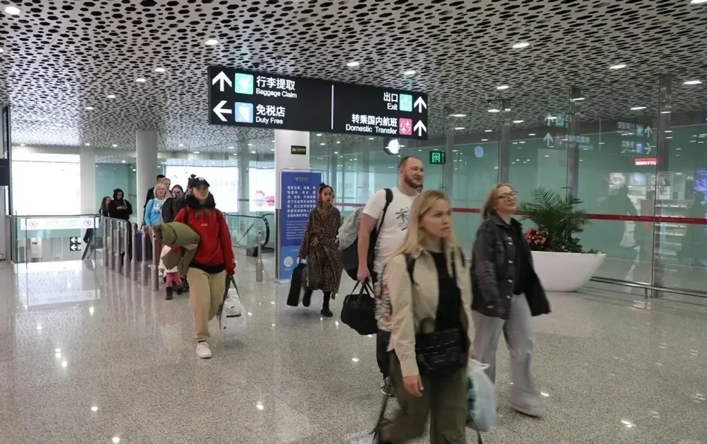 International travelers walking through Shenzhen airport arrivals hall, a common gateway for guided China tours