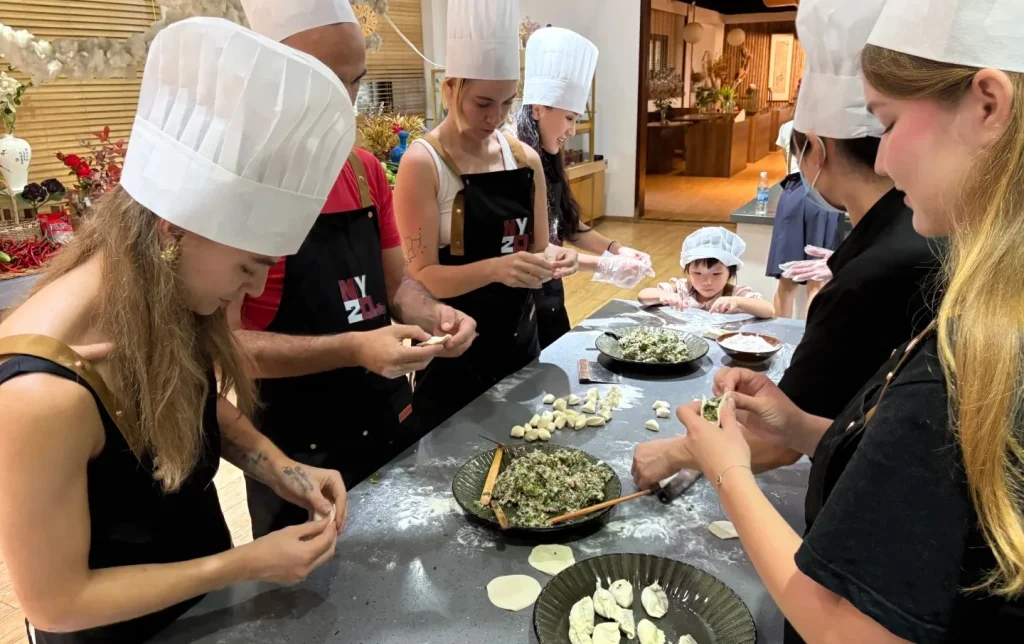 International visitors learning to make Chinese dumplings at a Xi'an cooking class, a hands-on highlight on private Xi'an food tours