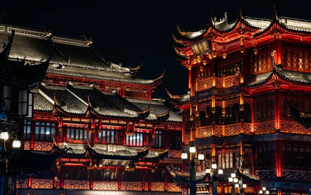 Dramatic night view of Yuyuan Temple's ornate multi-eave towers glowing red and gold against a dark sky — Shanghai City God Temple night photography