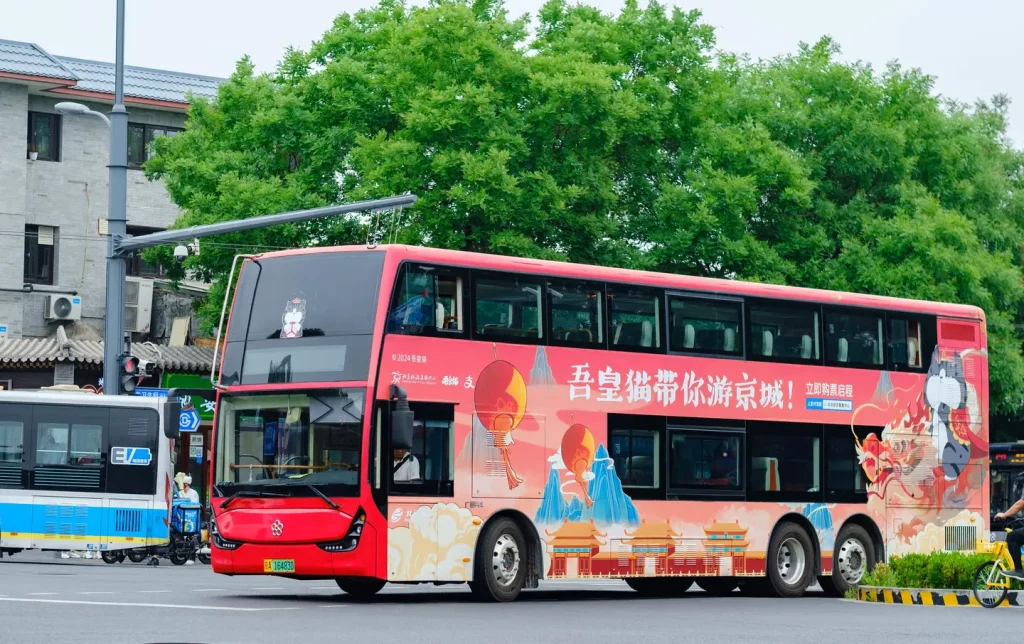Red double-decker sightseeing tourist bus with traditional Chinese themed wrap driving through central Beijing, a convenient way to explore the city on Beijing hop-on hop-off tours