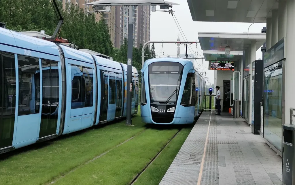 Modern blue trams at a grass-track station in a Chinese city, an eco-friendly urban transport experience on China city tours